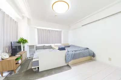 a white bedroom with a bed and a television at Maison Junes 21 in Tokyo