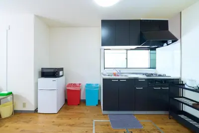 a kitchen with black cabinets and a white refrigerator at Kita-Shinjuku INN House in Tokyo