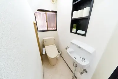 a white bathroom with a toilet and a sink at Kita-Shinjuku INN House in Tokyo