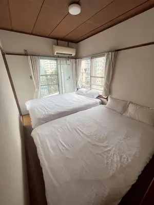 two twin beds in a room with a window at \u83ef -Hana- in Tokyo