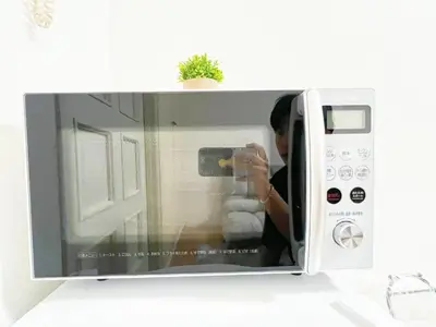 a woman taking a picture of a microwave at Ikebukuro Cozy \u30cf\u30a6\u30b95 in Tokyo