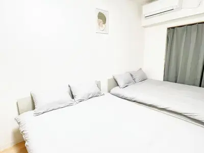 two beds in a room with white walls at Ikebukuro Cozy \u30cf\u30a6\u30b95 in Tokyo