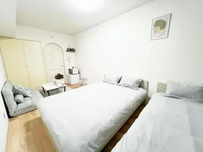 a white bedroom with a large bed and a chair at Ikebukuro Cozy \u30cf\u30a6\u30b95 in Tokyo