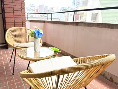 a balcony with two chairs and a table with a vase of flowers at Ikebukuro 2Room D3 in Tokyo