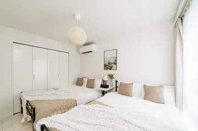two beds in a bedroom with white walls at Brand New Luxury Suite 7 min to Omotesando 2 min to Shibuya in Tokyo