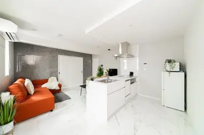 a living room with an orange couch and a kitchen at Brand New Luxury Suite 7 min to Omotesando 2 min to Shibuya in Tokyo