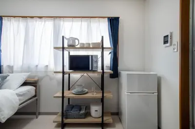 a room with a bed and a microwave and a refrigerator at CraftFlat Numabukuro 301, uphill residence in Tokyo