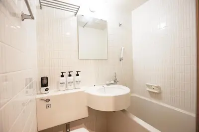 a white bathroom with a sink and a bath tub at \u6b4c\u821e\u4f0e\u753a\u306e\u4e2d\u5fc3 \u30c9\u30f3\u30ad\u30db\u30fc\u30c6 \u4f0a\u52e2\u4e39\u65b0\u5bbf\u3078\u4fbf\u5229 \u89b3\u5149 \u30b7\u30e7\u30c3\u30d4\u30f3\u30b0 \u30b0\u30eb\u30e1\u304c\u5f92\u6b69\u570f\u306e\u90fd\u5e02\u578b\u5bbf QoSi in Tokyo