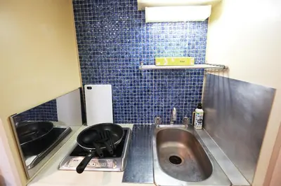 a small kitchen with a sink and blue tiles at \u6b4c\u821e\u4f0e\u753a\u306e\u4e2d\u5fc3 \u30c9\u30f3\u30ad\u30db\u30fc\u30c6 \u4f0a\u52e2\u4e39\u65b0\u5bbf\u3078\u4fbf\u5229 \u89b3\u5149 \u30b7\u30e7\u30c3\u30d4\u30f3\u30b0 \u30b0\u30eb\u30e1\u304c\u5f92\u6b69\u570f\u306e\u90fd\u5e02\u578b\u5bbf QoSi in Tokyo
