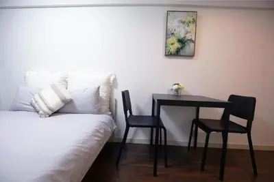 a bedroom with a table and chairs next to a bed at \u6b4c\u821e\u4f0e\u753a\u306e\u4e2d\u5fc3 \u30c9\u30f3\u30ad\u30db\u30fc\u30c6 \u4f0a\u52e2\u4e39\u65b0\u5bbf\u3078\u4fbf\u5229 \u89b3\u5149 \u30b7\u30e7\u30c3\u30d4\u30f3\u30b0 \u30b0\u30eb\u30e1\u304c\u5f92\u6b69\u570f\u306e\u90fd\u5e02\u578b\u5bbf QoSi in Tokyo