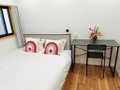 a bedroom with a table and a bed with pink pillows at \u6d45\u8349\u82b1\u65e5\u7f8e\u5c45 Asakusa Hanahi 305 Queen Bed Room, 4 min walk to Asakusa Temple, direct subway access to Narita and Haneda Airport in Tokyo