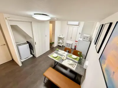 a room with a table and chairs and a kitchen at Sogno House Tokyo Ueno in Tokyo