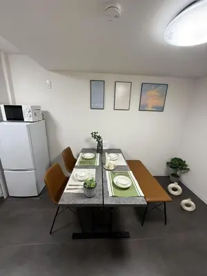 a dining room with a table with chairs and a refrigerator at Sogno House Tokyo Ueno in Tokyo