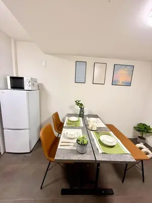 a kitchen with a table with chairs and a refrigerator at Sogno House Tokyo Ueno in Tokyo