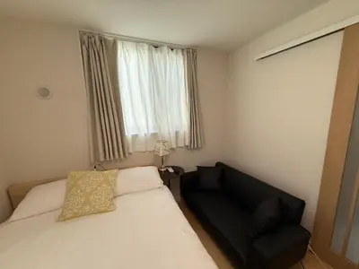 a bedroom with a bed and a chair and a window at \u3055\u304f\u3089\u65c5\u9928\u9ad8\u5186\u5bfa\u5317\u5343\u5229\u4f11201\u53f7\u5ba4 in Tokyo
