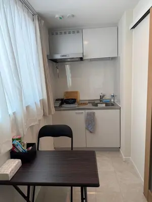 a small kitchen with a wooden table and a small table and a chair at \u3055\u304f\u3089\u65c5\u9928\u9ad8\u5186\u5bfa\u5317\u5343\u5229\u4f11201\u53f7\u5ba4 in Tokyo