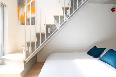 a bedroom with a bed and a staircase at PASEO\u5e02\u8c37\u53f0\u753al in Tokyo