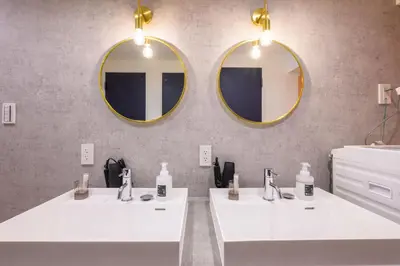 two sinks in a bathroom with two mirrors at TOMARU Meguro in Tokyo