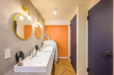 a bathroom with two sinks and an orange wall at TOMARU Meguro in Tokyo