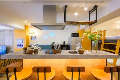 a kitchen with a large island with wooden chairs at TOMARU Meguro in Tokyo