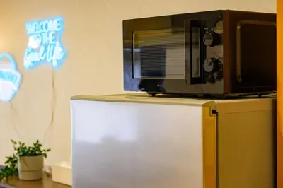 a microwave sitting on top of a refrigerator at TOMARU Meguro in Tokyo