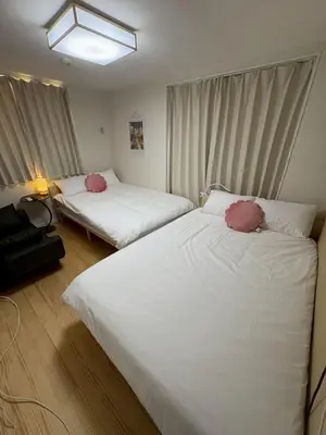 two beds in a room with white sheets and pink pillows at \u3055\u304f\u3089\u65c5\u9928\u9ad8\u5186\u5bfa\u5317\u5343\u5229\u4f11202\u53f7\u5ba4 in Tokyo