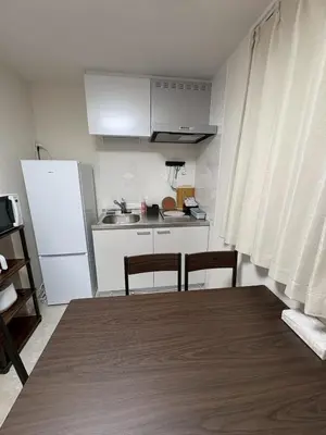 a kitchen with a white refrigerator and a table and chairs at \u3055\u304f\u3089\u65c5\u9928\u9ad8\u5186\u5bfa\u5317\u5343\u5229\u4f11202\u53f7\u5ba4 in Tokyo