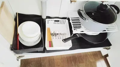 a kitchen cabinet with dishes and a bucket in it at Yoshiya in Tokyo