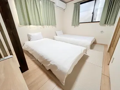 two beds in a small room with a window at Shinjuku Homely House 4Rooms-D in Tokyo
