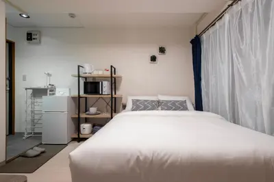 a bedroom with a large white bed and a window at CraftFlat Numabukuro 302, uphill residence in Tokyo