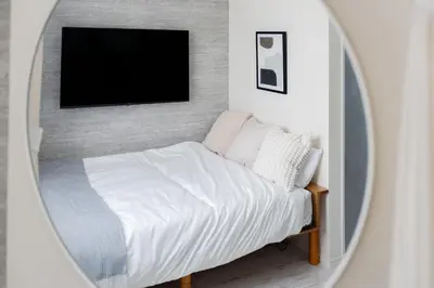 a mirror reflecting a bedroom with a bed and a tv at Intervia Horikiri in Tokyo