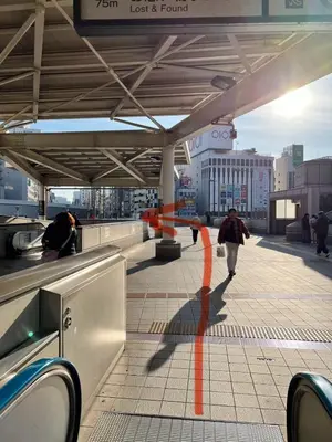 a person walking down a sidewalk with an orange line on a building at Ueno358 in Tokyo