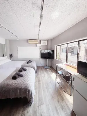 two beds in a room with a desk and a television at Ueno358 in Tokyo