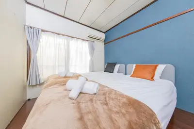 two beds in a room with a blue wall at Hanna Inn SHIBUYA 102 in Tokyo