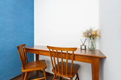 a wooden table with two chairs and a vase of flowers at Hanna Inn SHIBUYA 102 in Tokyo