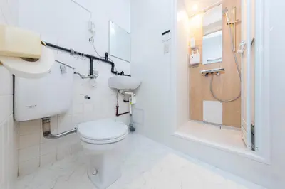 a white bathroom with a toilet and a shower at Hanna Inn SHIBUYA 102 in Tokyo