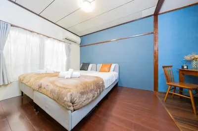 a bedroom with a bed and a blue wall at Hanna Inn SHIBUYA 102 in Tokyo
