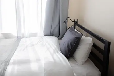 a bed with a pillow sitting next to a window at \u6771\u771f\u30d3\u30eb2\u968e \u7b39\u585a\u99c5\u304b\u3089\u5f92\u6b694\u5206 in Tokyo