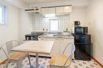 a kitchen with a table and a sink and a microwave at \u6771\u771f\u30d3\u30eb2\u968e \u7b39\u585a\u99c5\u304b\u3089\u5f92\u6b694\u5206 in Tokyo