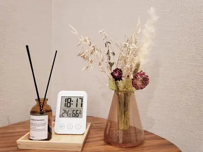 a vase with flowers in it next to an alarm clock at Komorebi Rill \u6d45\u8349 in Tokyo
