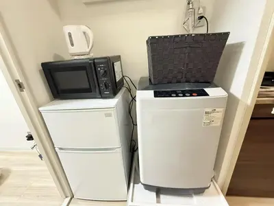 a microwave sitting on top of two refrigerators at Ikebukuro IVY House Ao6 in Tokyo