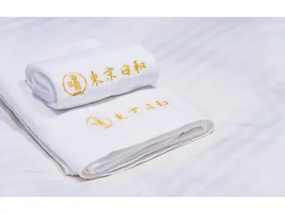 a white towel with gold writing on it on a bed at Tokyo Biyori Hotel - Vacation STAY 07403v in Tokyo