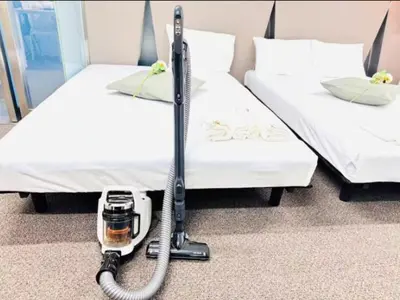 a vacuum cleaner on the floor between two beds at \u6771\u4eac\u90fd\u5fc3\u5b8c\u5168\u8cb8\u5207 \u6620\u753b\u5ba4\u6c60\u888b\u96fb\u8eca6\u5206\u65b0\u5bbf\u6e0b\u8c37\u76f4\u901aWiFI \u9577\u671fOK WAGAMAMA\u5c0f\u7af9\u5411\u539fFUJI 101\u5ba4 in Tokyo