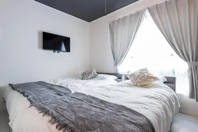 a bedroom with a bed and a tv and a window at Forest Side Yoyogi Park 202 in Tokyo