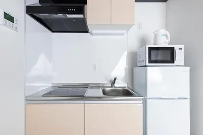 a white kitchen with a sink and a microwave at Forest Side Yoyogi Park 202 in Tokyo
