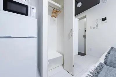 a small white kitchen with a microwave above a refrigerator at Forest Side Yoyogi Park 202 in Tokyo