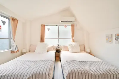 two beds in a room with a window at Tomo House Oshiage - from 2 minutes station \u62bc\u4e0a \u99c5\u304b\u3089\u5f92\u6b692\u5206 in Tokyo