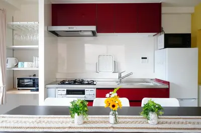 a kitchen with red and white cabinets and a counter with flowers at Tomo House Oshiage - from 2 minutes station \u62bc\u4e0a \u99c5\u304b\u3089\u5f92\u6b692\u5206 in Tokyo