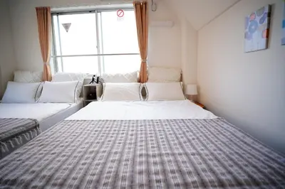 a bedroom with two beds in front of a window at Tomo House Oshiage - from 2 minutes station \u62bc\u4e0a \u99c5\u304b\u3089\u5f92\u6b692\u5206 in Tokyo