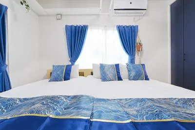 a bedroom with a large bed with blue curtains at Tomo House Otsuka - from 6 minutes station \u5927\u585a \u99c5\u304b\u3089\u5f92\u6b696\u5206 in Tokyo